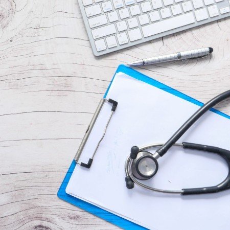 A clipboard and medical equipment on a table. 